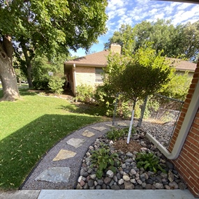 Curved crushed granite and stepping-stone path beside a landscaped backyard gate