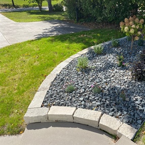 Close-up of a curved limestone landscape border with trap rock and ornamental plants