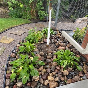 Crushed granite path, flagstone steppers, and river rock bed beside a backyard gate