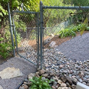 Crushed granite walkway and river rock border beside a backyard gate
