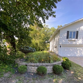 Overgrown circular concrete planter before landscape renovation at a Golden Valley, MN home