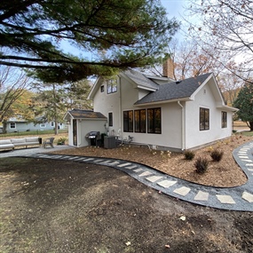 Curved flagstone path extending around a Buffalo home toward the backyard