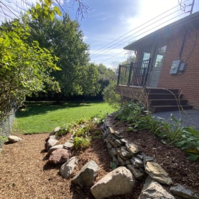 Reconstructed flagstone garden terraces and low-maintenance mulched path beside a deck