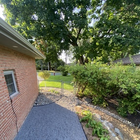 Crushed granite walkway installed beside a brick home and backyard fence